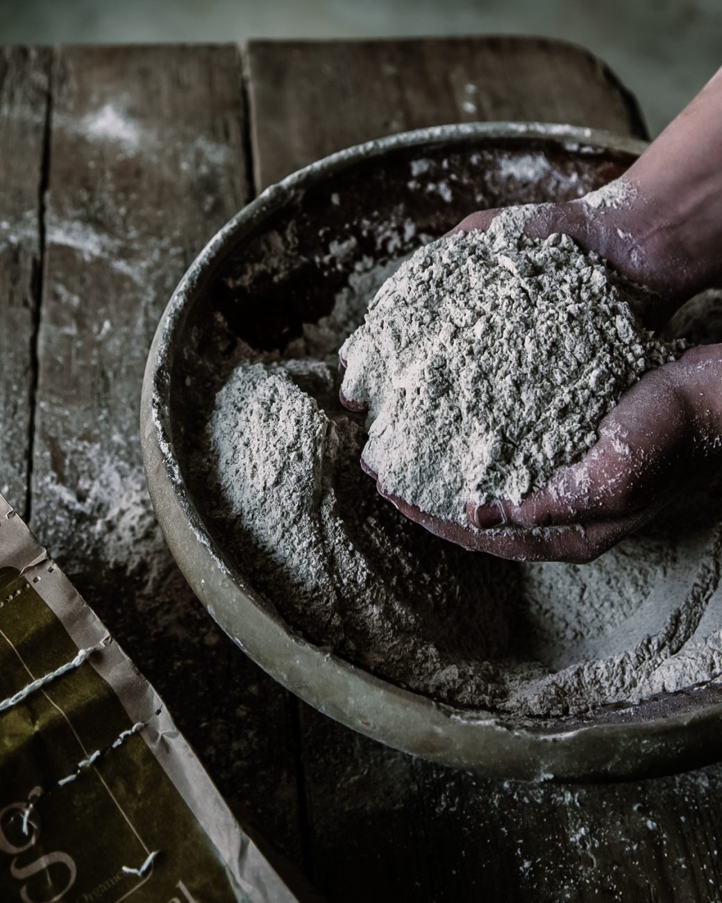Freshly-milled flour scooped up in a baker's hands ready for use