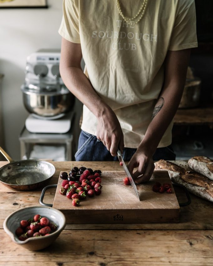 Person chopping berries on a wooden board. Berries are full of polyphenols which can prevent neurodegeneration.