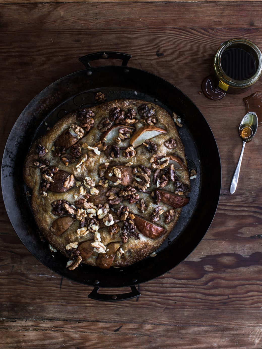 Top view of an autumn pear, honey, and walnut flatbread, featuring a golden-brown crust and garnished with fresh pear slices, walnuts, and a drizzle of honey.