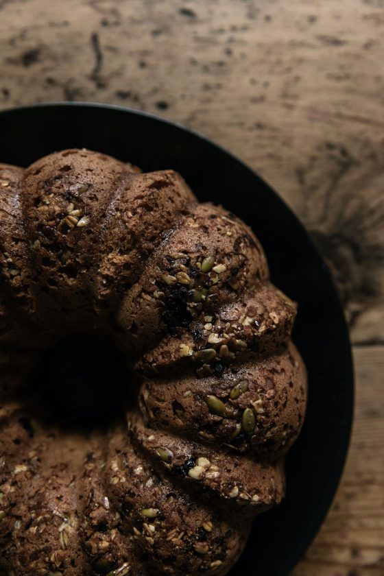 Close up of seeded bundt sweet sourodough on a black plate ontop of a wooden table.